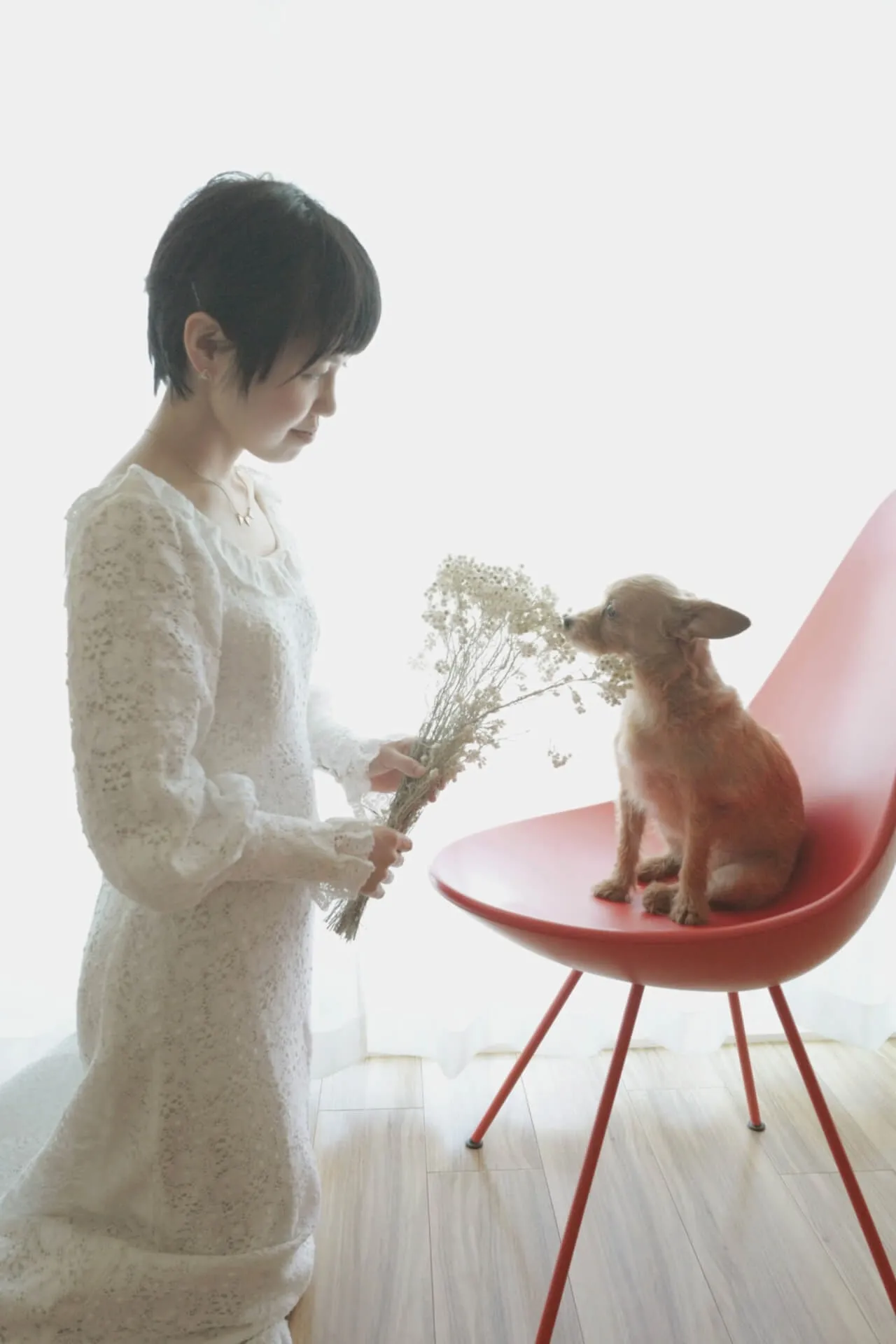 犬と一緒に微笑む白い服の女性