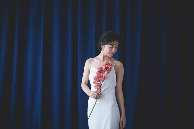 青いカーテンの前に立つ花嫁